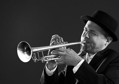 Kreatives Businessportrait Künstler, Musiker mit Trompete und Hut